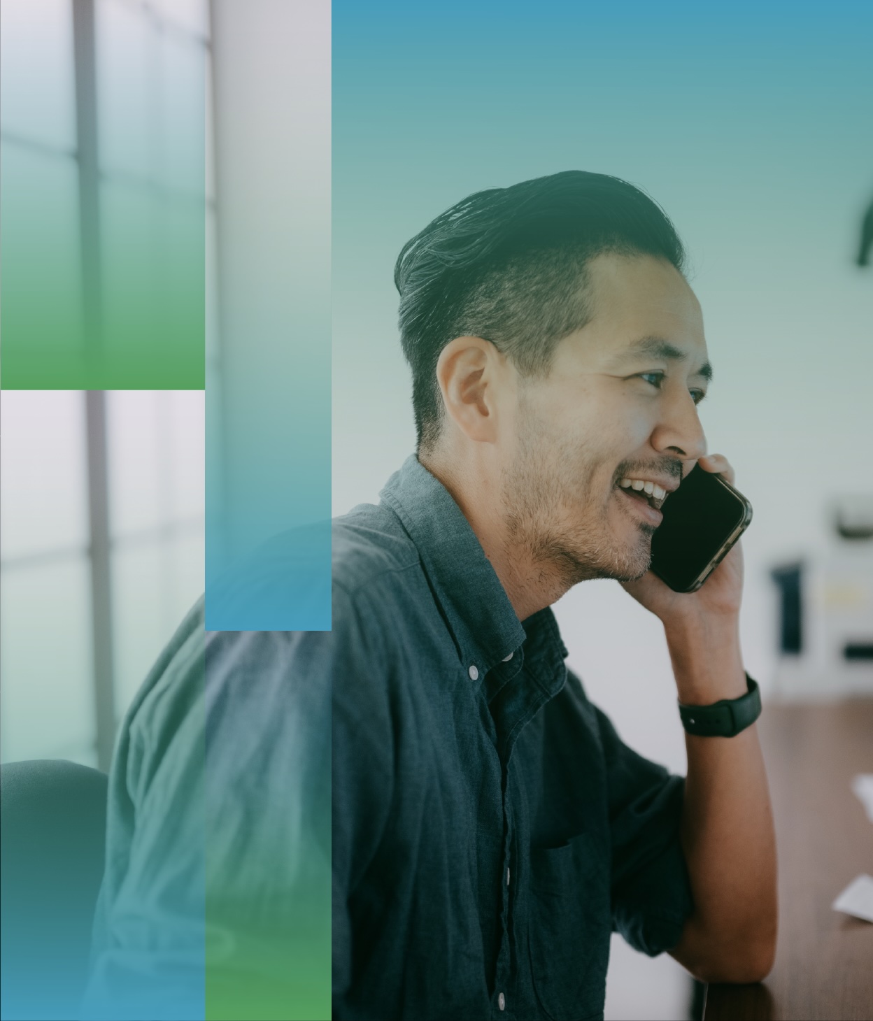 Person seated indoors, holding a smartphone to one ear while wearing a long-sleeve button-up shirt, with abstract green and blue translucent graphic shapes overlaid on the image and a softly lit office-style background.