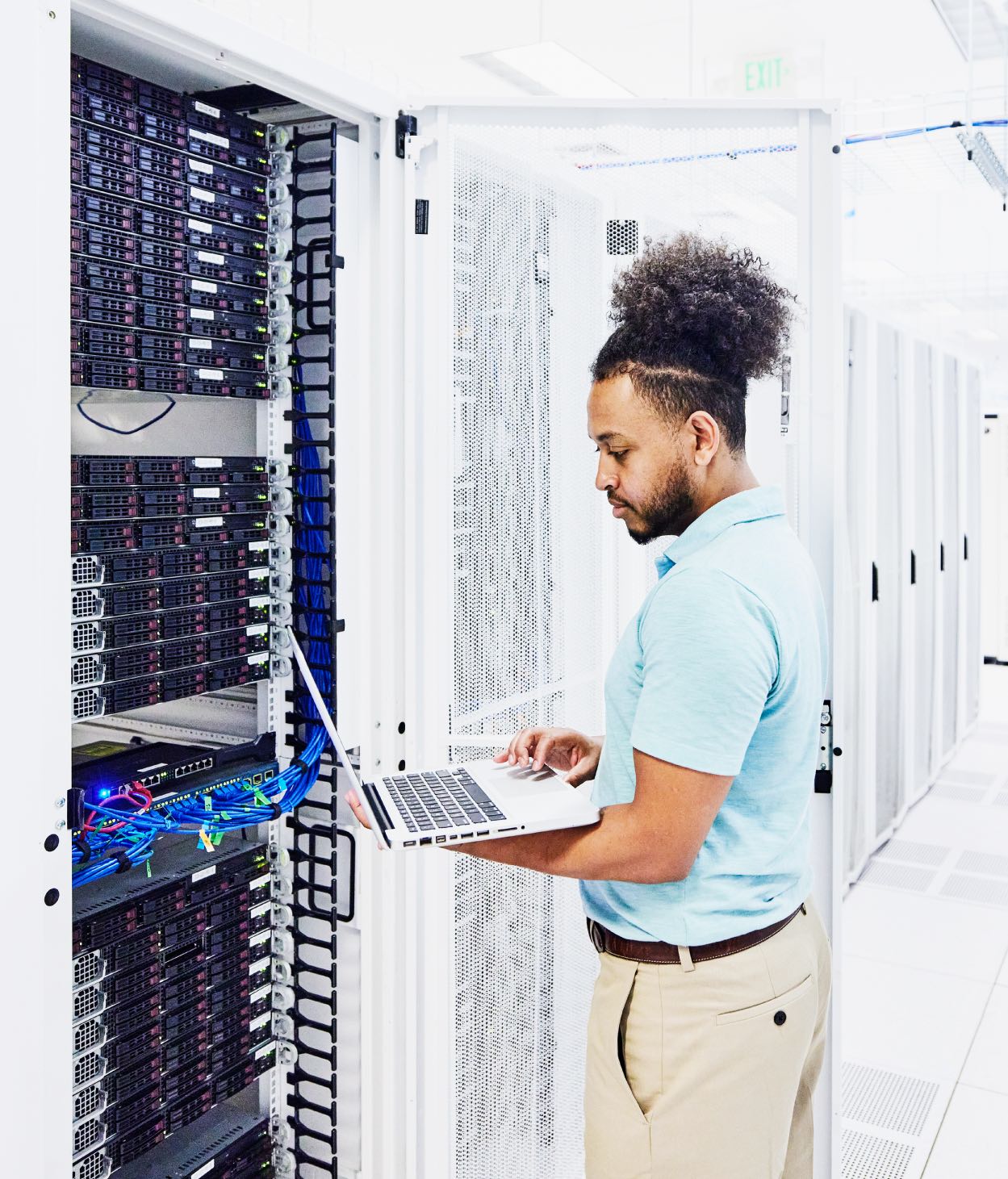 IT employee diagnoses server equipment in a server room.